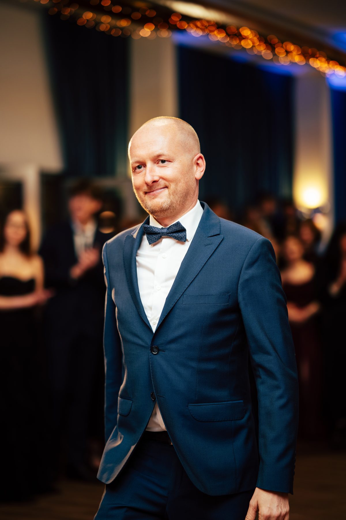 Portret gościa studniówki w granatowym garniturze i muszce