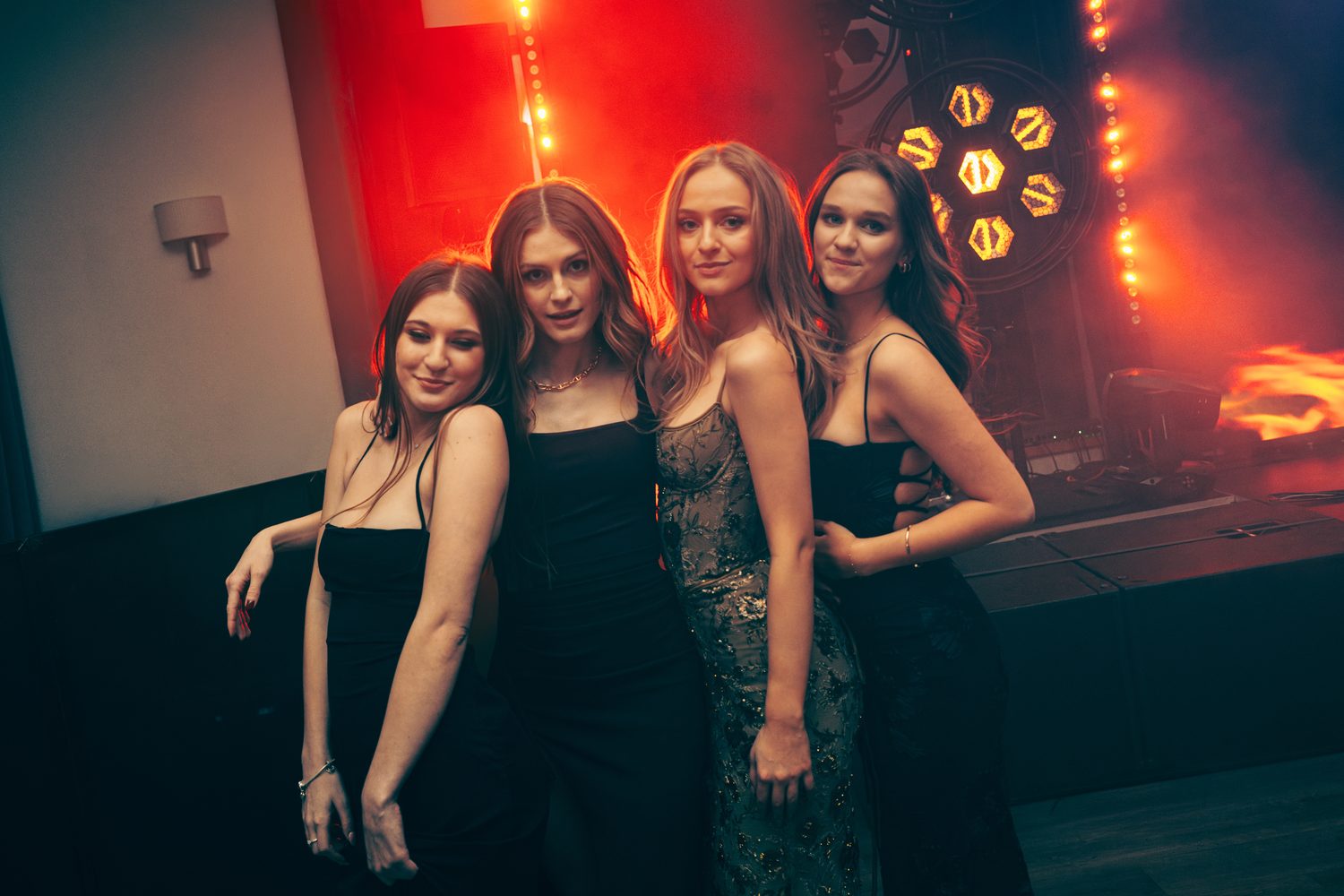 Cztery uczestniczki studniówki pozują w czerwonym świetle sali